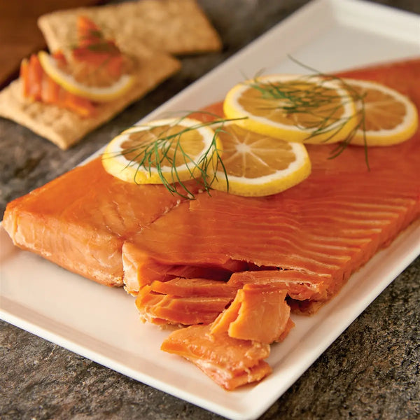wholeside of wild pink smoked salmon retort on a plate with sliced lemons and dill